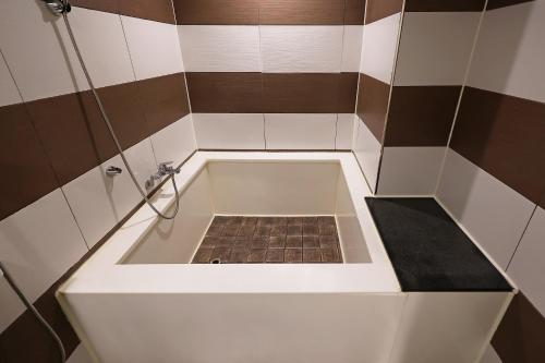 a small bathroom with a tub with a tile floor at Hotel Gem in Busan