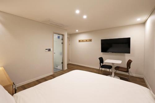 a bedroom with a bed and a desk and a tv at Hotel Gem in Busan