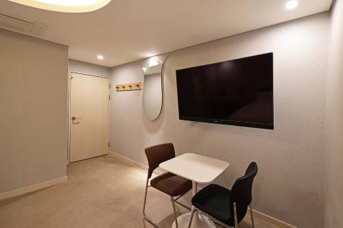a room with a table and chairs and a tv on the wall at Hotel Gem in Busan