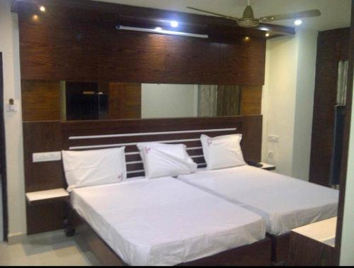 a bedroom with a large white bed with a wooden headboard at HoTEL TANIYA in Vijayawāda