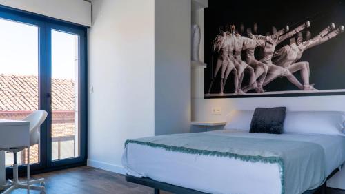 a bedroom with a bed with a painting on the wall at Apartamentos Identia Sport by gaiarooms in León