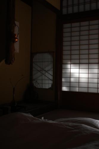 a dark room with a bed and a window at UTAHI  A 100-years-old Kyoto machiya in Kyoto