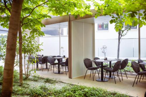 a group of tables and chairs in a room with trees at MOOONS Vienna in Vienna