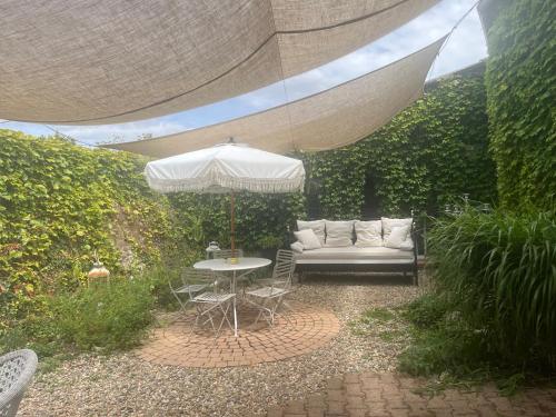 a patio with a white couch and an umbrella at La Closeraie Saint Girons in Saint-Girons-dʼAiguevives