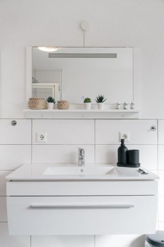 a white bathroom with a sink and a mirror at FeriendomizilaufderZollernalb in Albstadt
