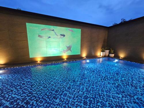 a swimming pool with a projection screen on a building at luxury poolvilla first in Pajak