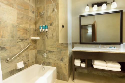 a bathroom with a tub and a sink and a mirror at Drury Plaza Hotel in Santa Fe in Santa Fe