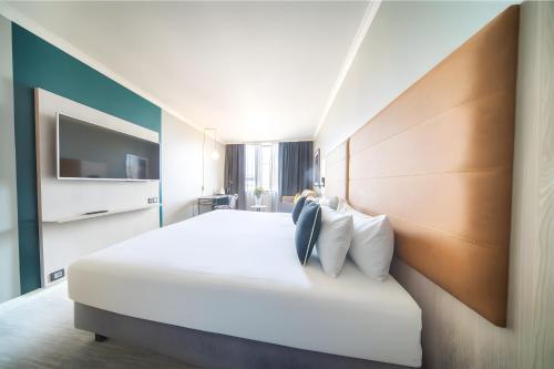 a hotel room with a large white bed and a tv at Maek Hotel Antwerp Central - Handwritten Collection in Antwerp