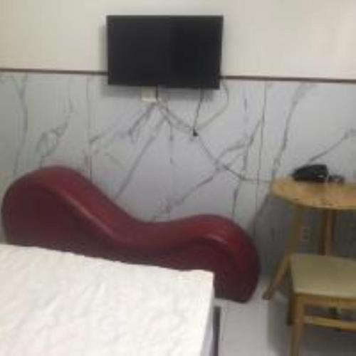a red chair in a room with a tv on the wall at Du Thuyền 2 Hotel Hồ Chí Minh in Ho Chi Minh City