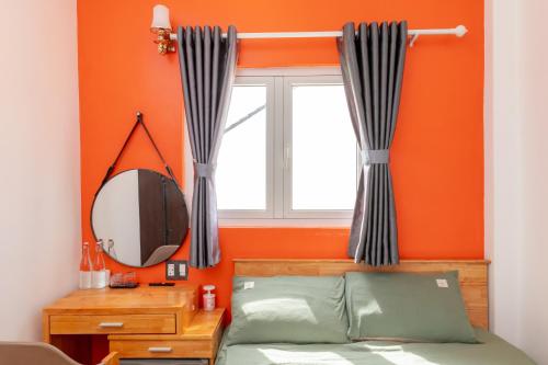a bedroom with an orange wall and a mirror at D Home Da Lat 3 in Da Lat