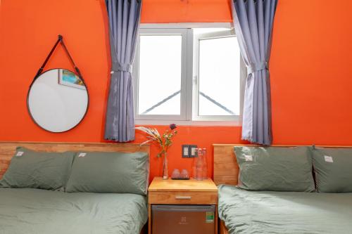 a bedroom with orange walls and a mirror and two beds at D Home Da Lat 3 in Da Lat