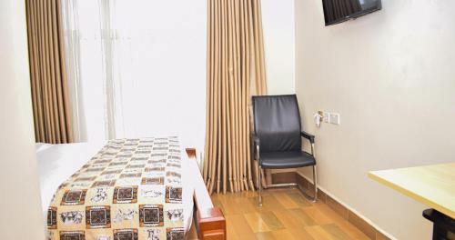 a bedroom with a bed and a chair in it at Pori City Hotel in Nairobi