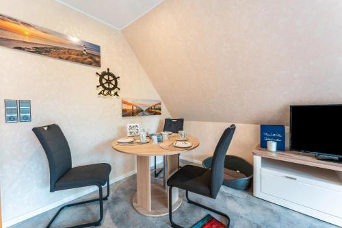 a dining room with a table and chairs and a tv at Fewo Lütt Stuv in Fockbek