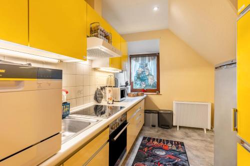 a kitchen with yellow cabinets and a sink at Fewo Lütt Stuv in Fockbek