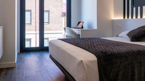 a bedroom with a bed and a desk and a window at Apartamentos Identia Sport by gaiarooms in León