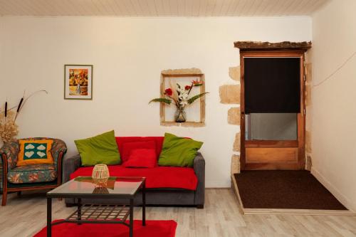 a living room with a red couch and green pillows at Gite Fil Rouge in Saint-Pierre-dʼAurillac