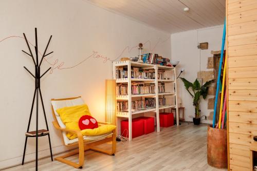 a living room with a chair and a book shelf at Gite Fil Rouge in Saint-Pierre-dʼAurillac