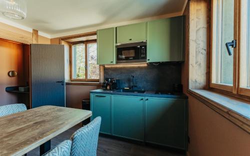 a kitchen with green cabinets and a table with chairs at La Tour de Contrôle - Chambres & Appartements in Challes-les-Eaux