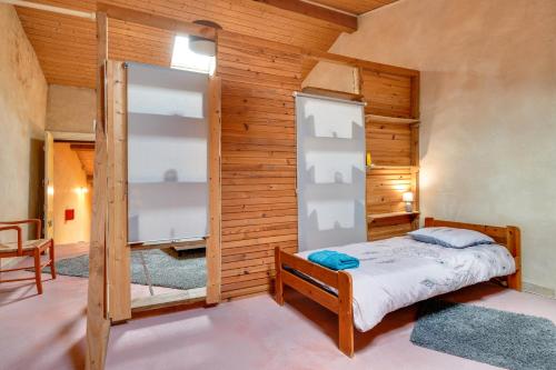 a bedroom with a bed and a wooden wall at Gite Fil Rouge in Saint-Pierre-dʼAurillac