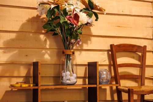 a vase with flowers on a shelf next to a chair at Gite Fil Rouge in Saint-Pierre-dʼAurillac