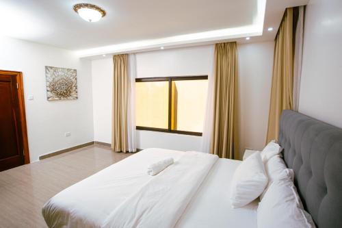 a bedroom with a white bed and a window at Durang Serviced Apartments in Lusaka