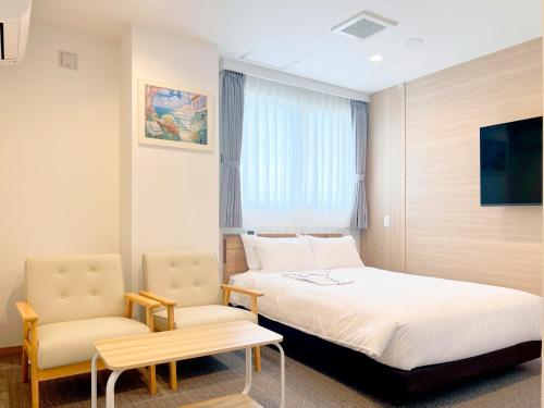 a hotel room with a bed and two chairs at ステラサイト函館 in Hakodate