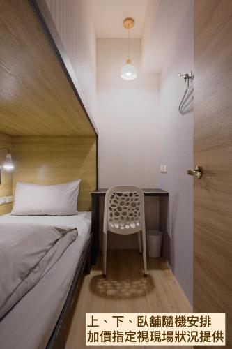 a bedroom with a bed and a chair next to a desk at Work Inn 101 慕誠青年旅館 in Taipei