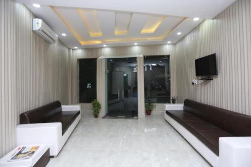 un salon avec deux canapés et une télévision dans l'établissement Premium Hotel The Param Suites A unit of Ramaansh Hotels - 650 Meters from Ram Mandir Ayodhya, à Ayodhya