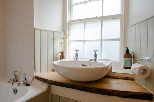 a bathroom with a white sink and a window at The Dell of Abernethy - A Woodland hideaway in Nethy Bridge