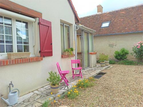 two pink chairs sitting on the side of a house at Caporizon - La Solognote in Bracieux