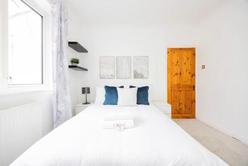 a white bedroom with a large white bed with blue pillows at 4 Bed in Caterham Contractors Leisure in Purley