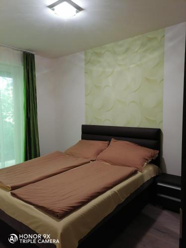 a bed in a bedroom with a green curtain at Perfekt Apartman Zamárdi in Zamárdi