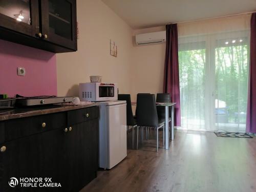 a kitchen with a microwave and a table with chairs at Perfekt Apartman Zamárdi in Zamárdi