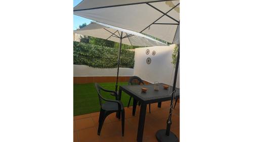 a table and chairs under an umbrella on a patio at La Casita de Rosi in Navaluenga