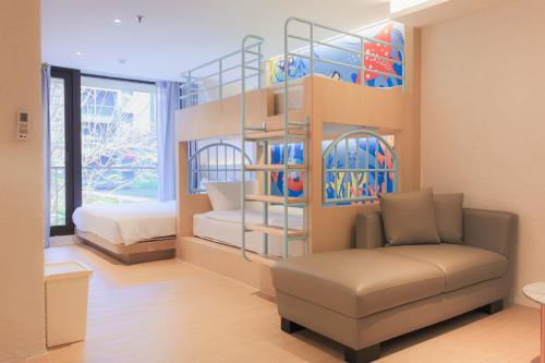 a living room with a couch and a bed in a room at Balcony Seaside Sriracha Hotel & Serviced Apartments in Si Racha