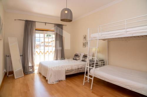 two bunk beds in a room with a window at Villa BelaVista by ACasaDasCasas in Ericeira