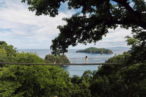 a person standing on a bridge over the water at Nekajui, a Ritz-Carlton Reserve in Papagayo, Guanacaste