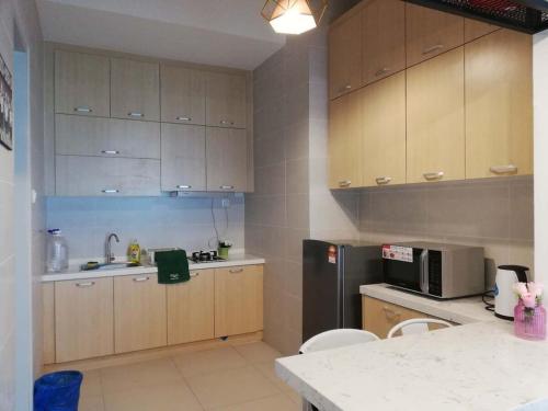a kitchen with wooden cabinets and a stainless steel refrigerator at Bukit Jalil Cozy Small Comfortable Home Suitable for a Family of 4 in Serdang