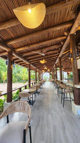 a row of tables and chairs under a wooden ceiling at Pineapple Beach Villas in Baie Lazare Mahé