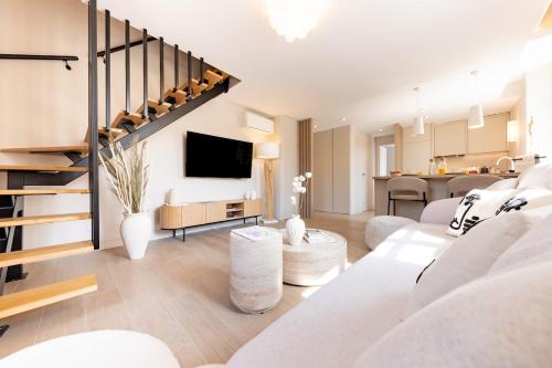 a living room with a white couch and a staircase at Élégant duplex 8 pers clim et suite parentale in Vallauris