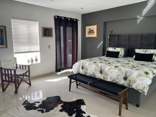 a bedroom with a large bed and a chair at Bed and Breakfast Villa Livadia in Cape Town