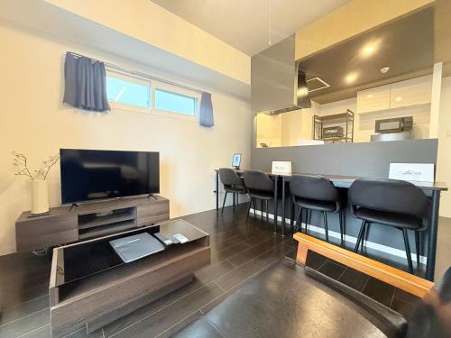 a living room with a bar with chairs and a television at Sun Court Nango-dori サンコート南郷通 501 in Sapporo