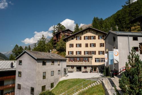 a large building in the middle of a group of buildings at Zermatt Youth Hostel in Zermatt