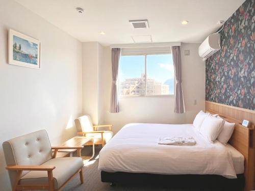 a hotel room with a bed and a chair and a window at ステラサイト函館 in Hakodate