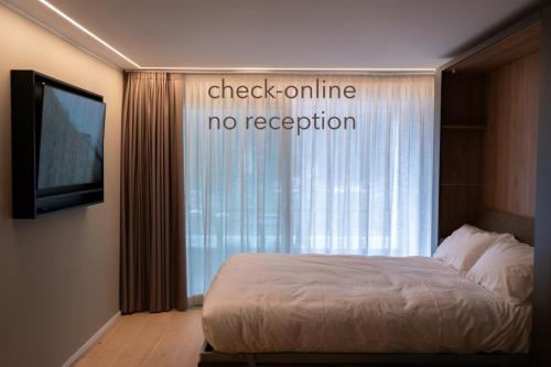 a bedroom with a bed and a tv and a window at Arbed Living Hotel SELF CHECK IN - Supercharger - Fitness Bellinzona in Bellinzona