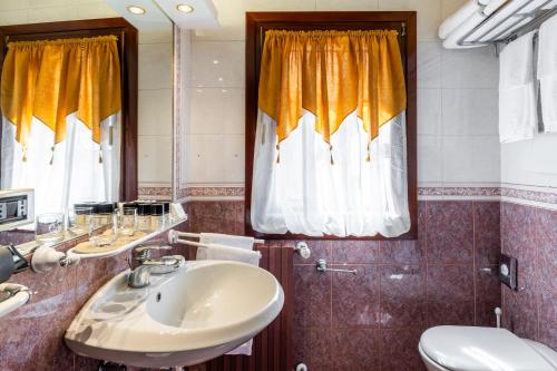 a bathroom with a sink and a toilet and a mirror at Hotel Locanda Remedio in Venice