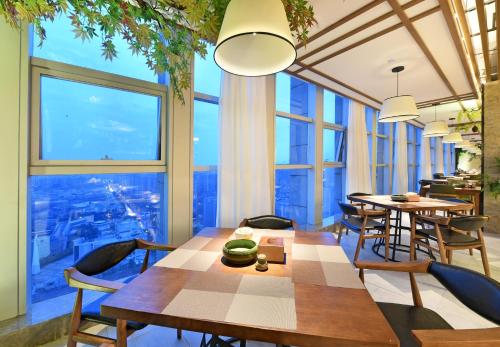 a dining room with a table and chairs and large windows at Mehood Lestie Hotel Chengdu Hi-Tech Zone in Chengdu