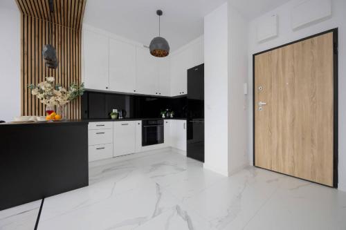 a kitchen with white cabinets and a wooden door at Nowe Sady Stylish Apartment Close to Łódź Airport by Noclegi Renters in Łódź