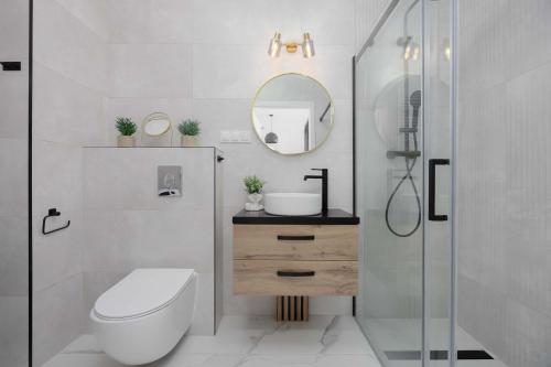 a bathroom with a toilet and a sink and a mirror at Nowe Sady Stylish Apartment Close to Łódź Airport by Noclegi Renters in Łódź