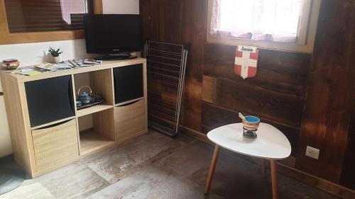 a room with a tv and a table with a stool at Apartement dans chalet a Jarrier in Jarrier